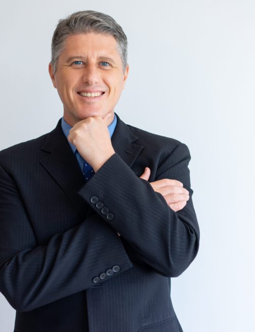 Portrait of positive confident businessman. Middle aged Caucasian man in jacket and tie touching chin and smiling at camera. Successful business leader concept
